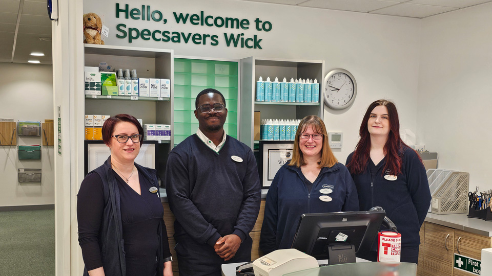 Four people in Specsavers uniform stand behind a reception desk for Specsavers Wick