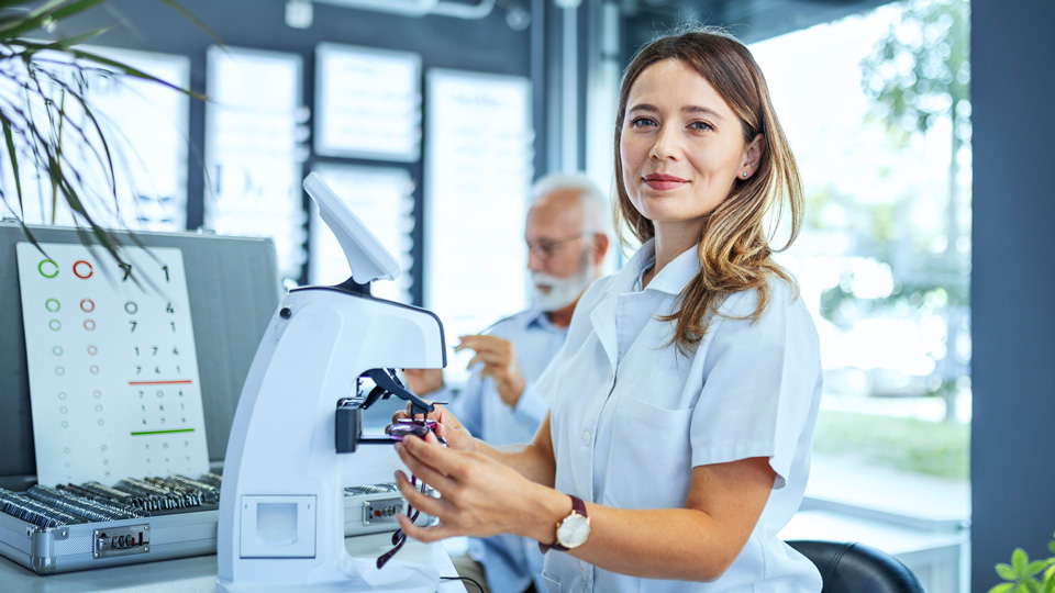 Young woman measuring glass on eyewear for a senior patient looking at camera