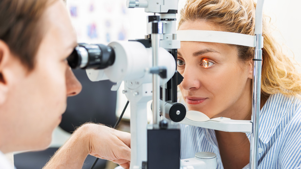 A professional woman is receiving an eye test from an optometrist
