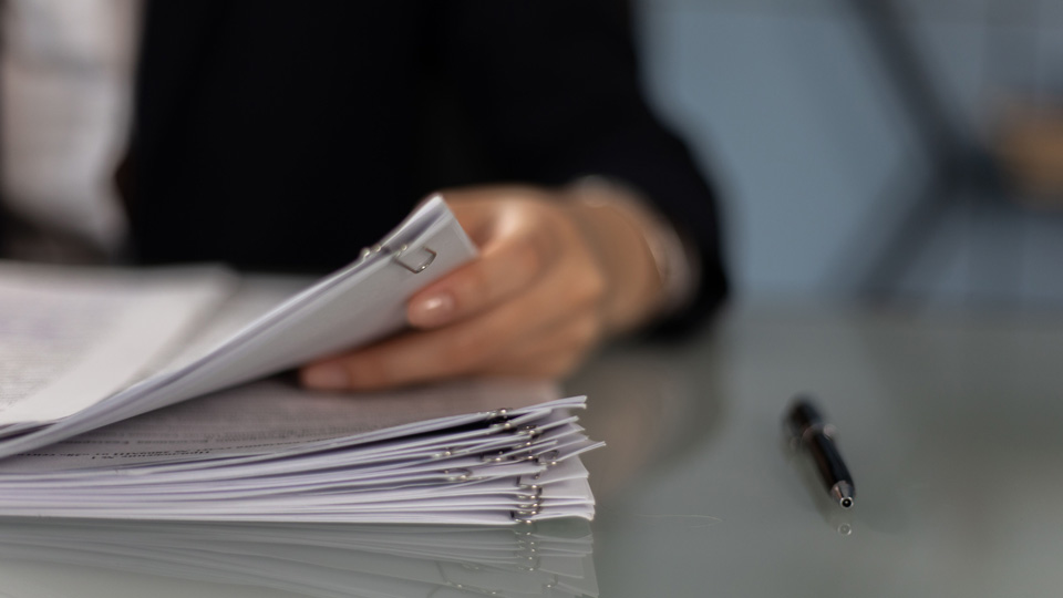 A close-up of a hand flicking through a pile of organised papers