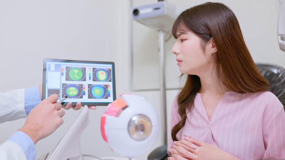 A patient sits in a consultation room as an eye scan is explained to her by a clinician