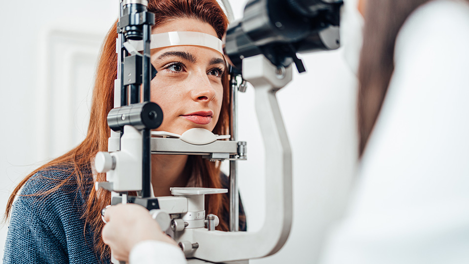 Young female adult sitting at equipment with head in rest having her sight tested