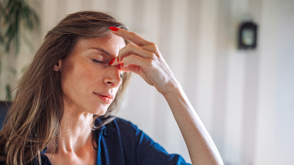 Woman with hand on forehead and eyes closed