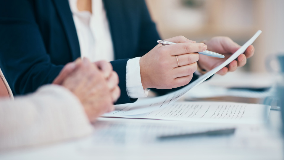 Hands holding a pen and bundle of paper