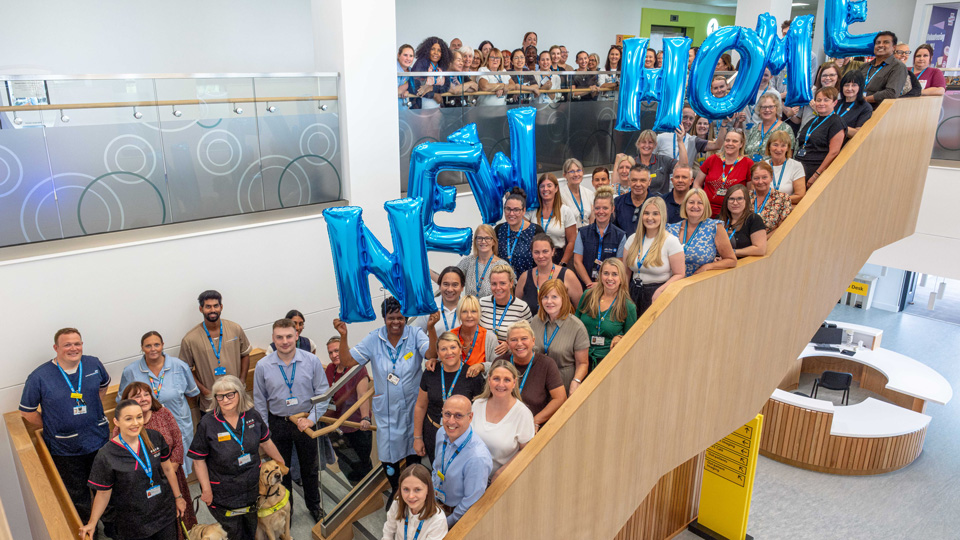 Staff from the Sunderland Specialist Eye Hospital gather on the main staircase of the new facility, holding up balloon letters that spell out ‘New Home’