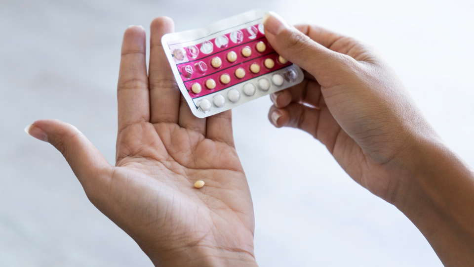 A woman holds a pack of oral contraceptives