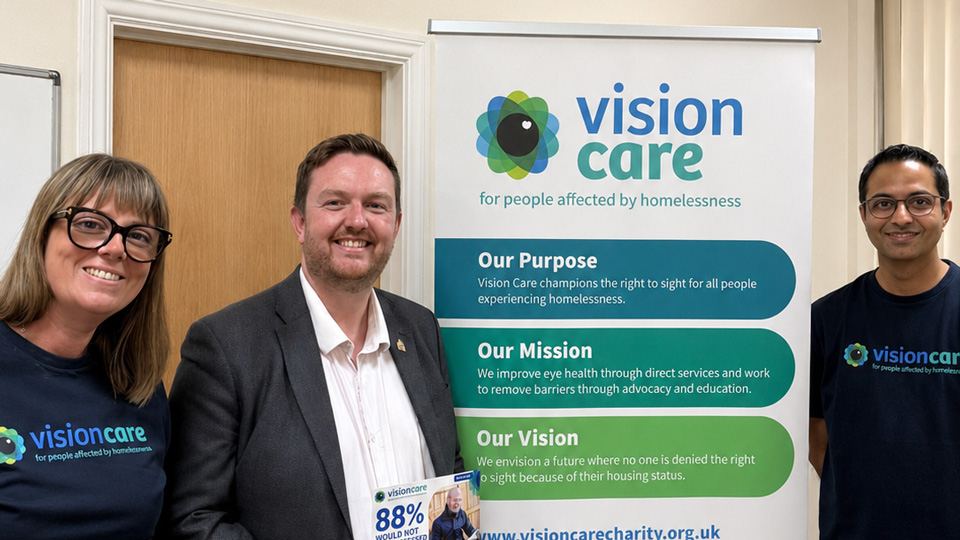 Hannah Telfer, left, Alex McIntyre MP, and Nikhil Sonpal stand around a Vision Care banner