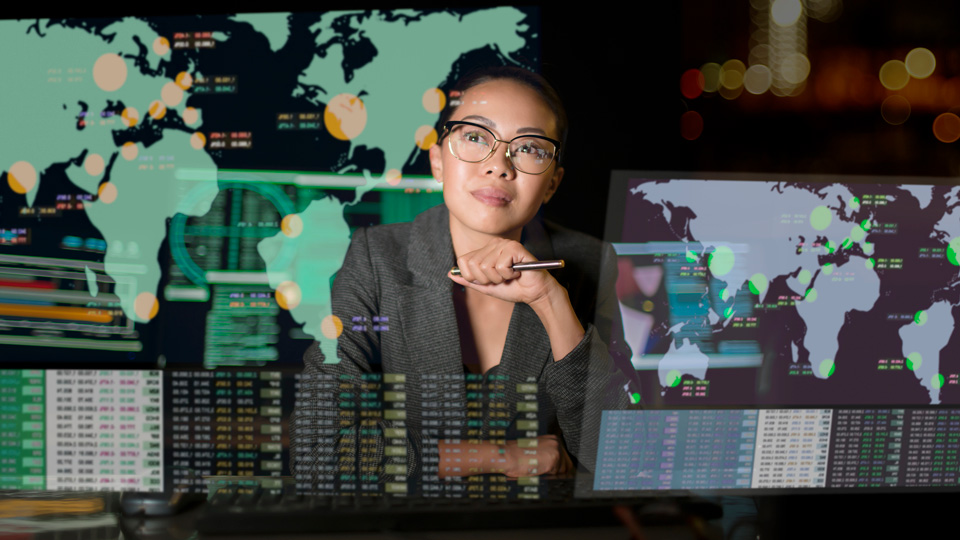 A woman looks at a projection displaying data and the world map