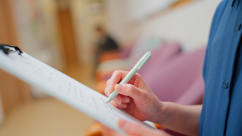 A person writes on a clipboard