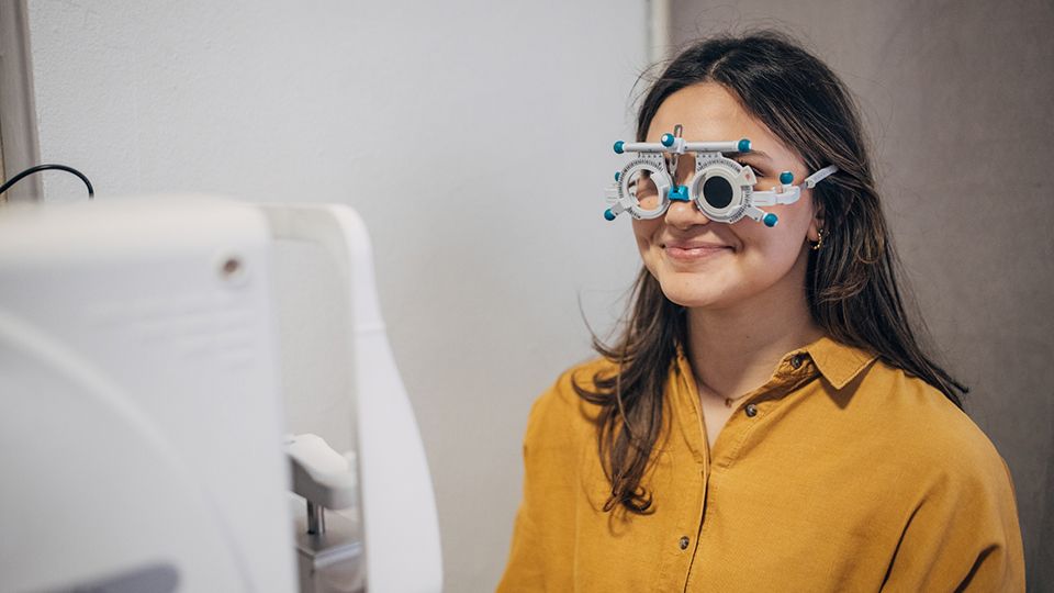A woman wearing a yellow top receives a sight test