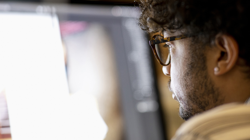 A man sits in front of a bright screen