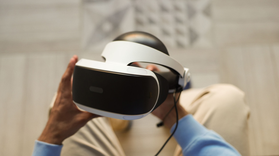 A person holds a virtal reality headset in their lap