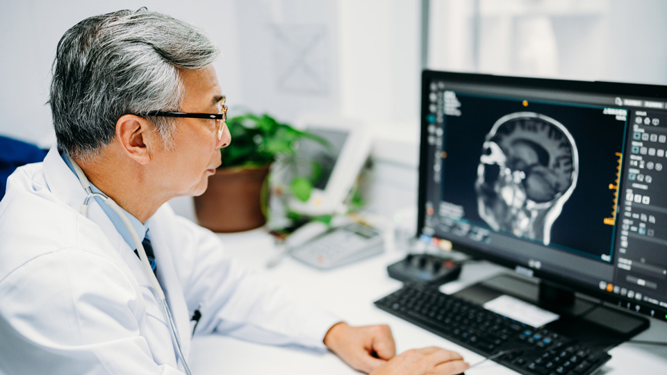 A clinician looks at a brain scan on a computer screen