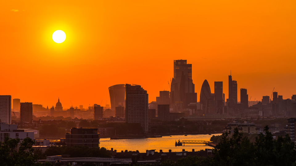 A photo of the London skyline illuminated orange at sunset