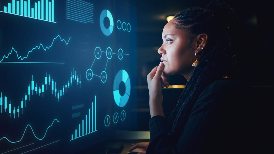 A woman concentrates on a screen with a series of graphs