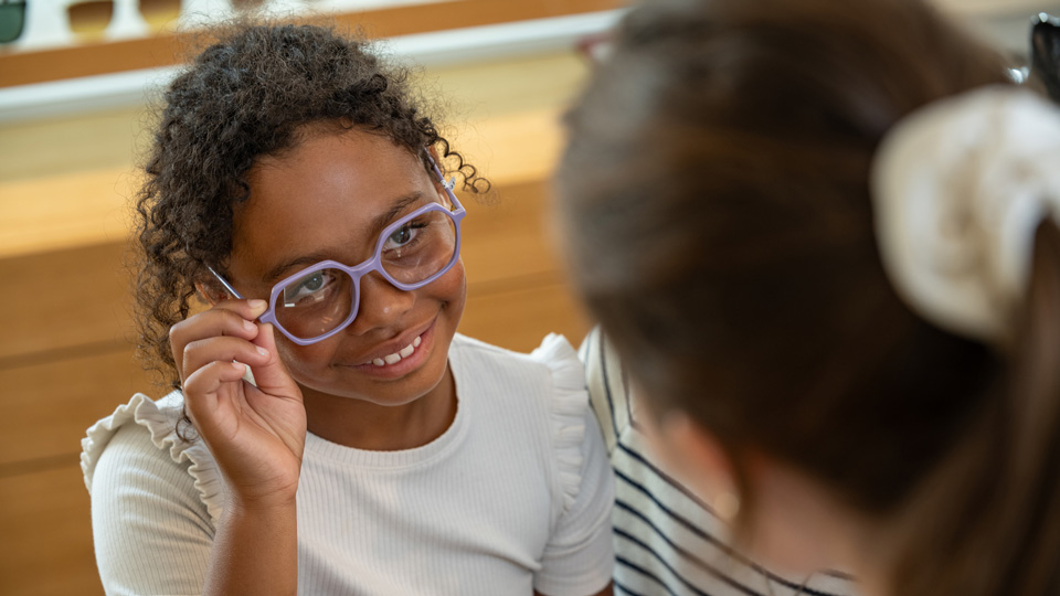 A girl tries on a pair of lilac glasses