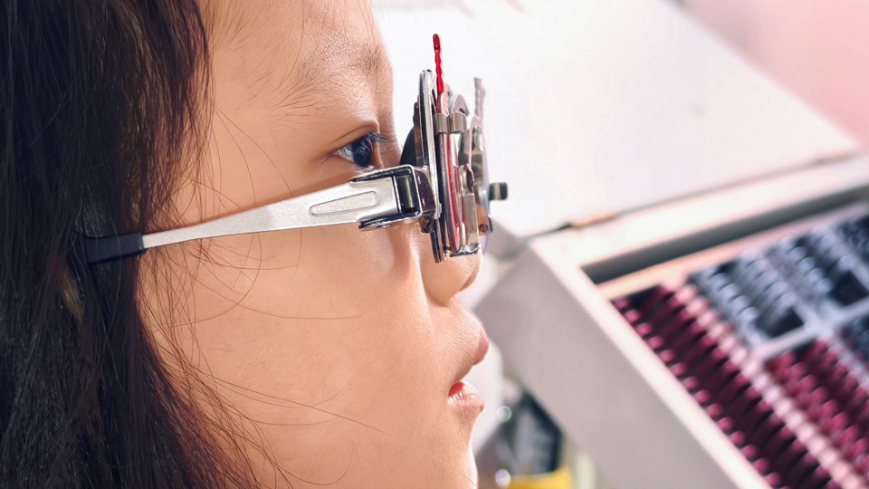 A girl pictured in profile has her vision tested with trial lenses