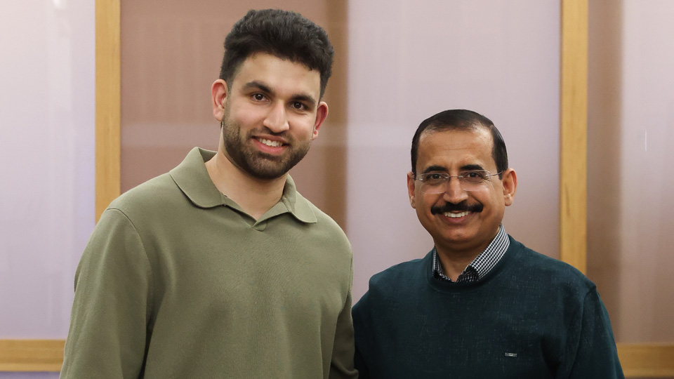 Umar, right, in a green long-sleeved polo shirt and jeans, stands next to his mentor Dr Saleh Al-Akily, who wears a dark jumper over a check shirt. They are behind a case with the SightWatcher logo
