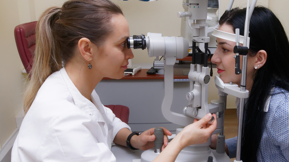 An optometrist performs a sight test on a young professional