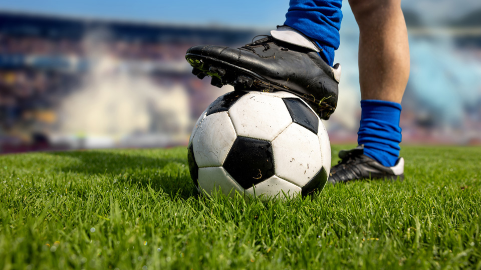 Close-up on a football player stepping on the ball at the field