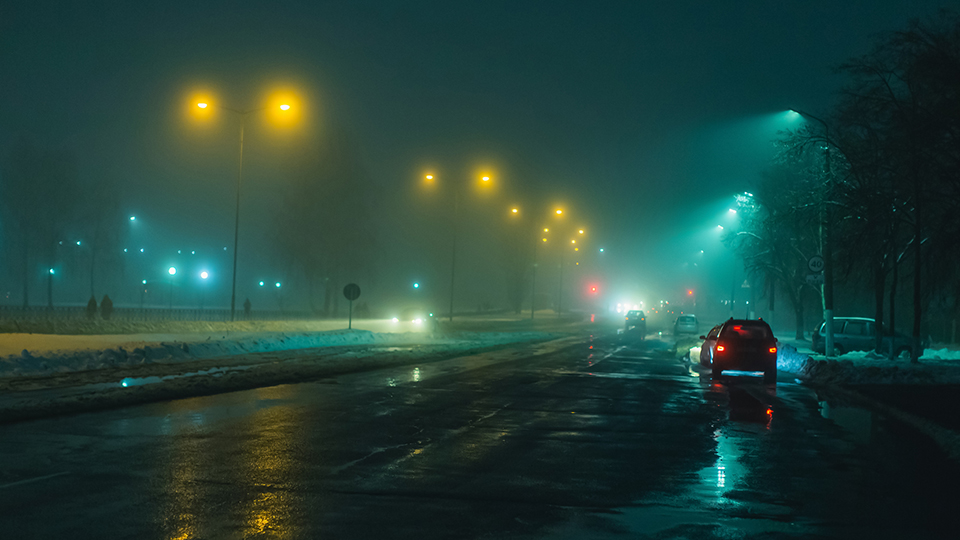 A road at night with cars on lined with street lights