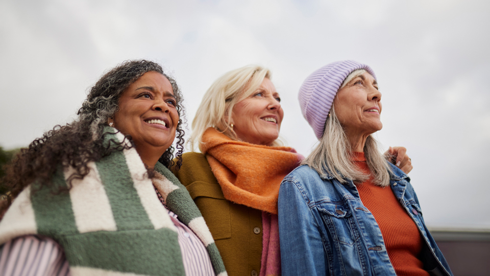 A group of three older women look at the horizon