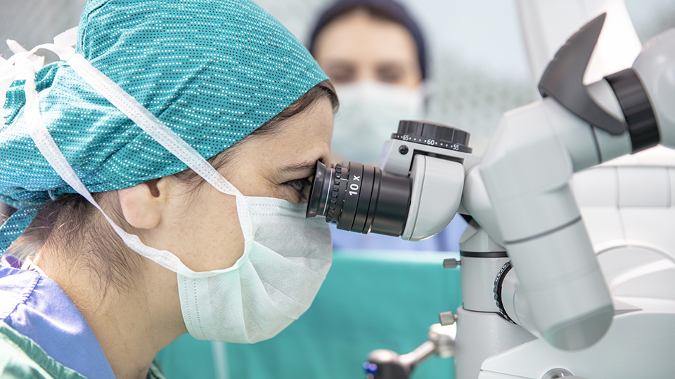 A surgeon looks through a microscope