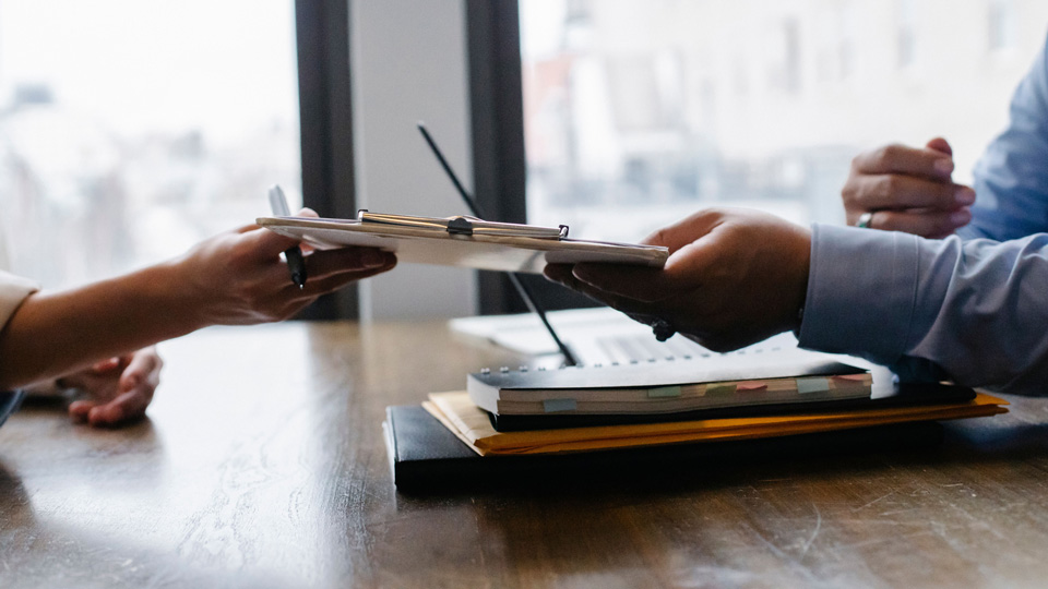 Two business people exchange documents