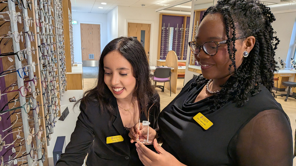 Two optometry students are looking at the frames in a new practice set up in a university environment