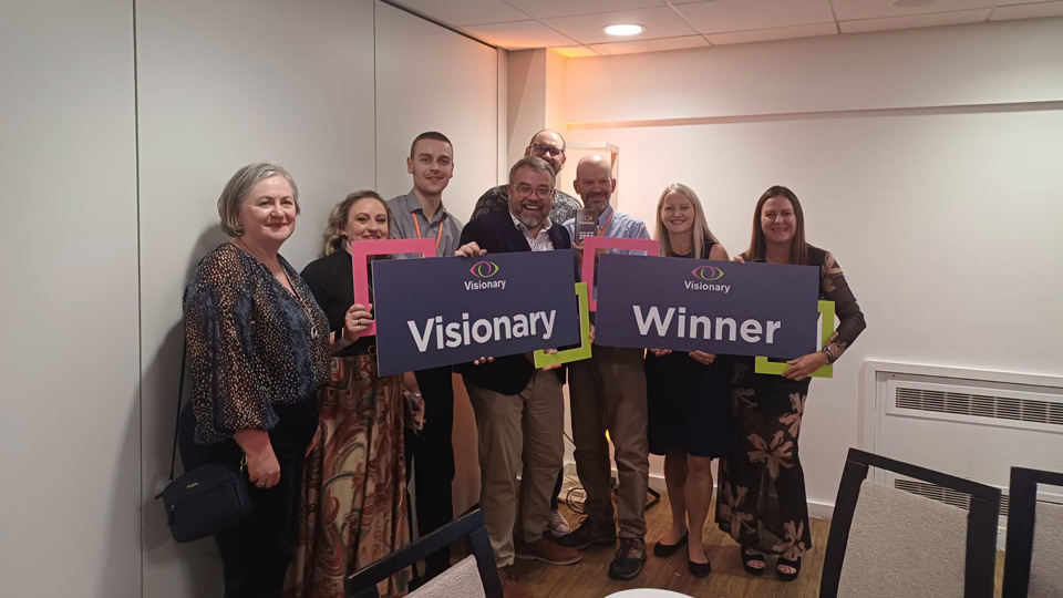 A group gather together, holding up signs for Visionary Award winners