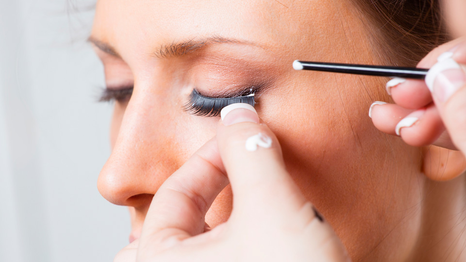 A cosmetic technician applies eyelash extensions