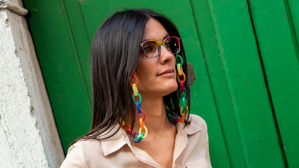 A woman wears colourful glasses and a matching chunky glasses frame in rainbow of colours