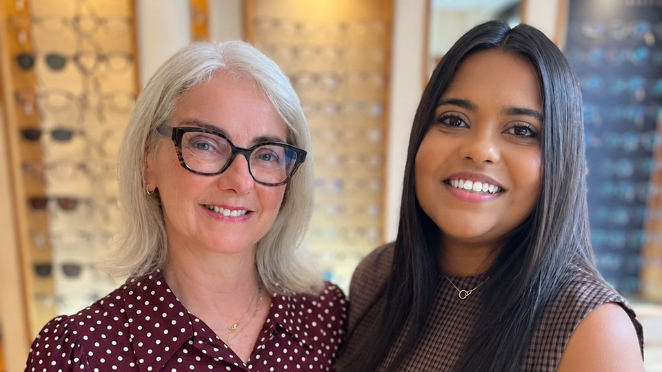 Two women stand together smiling