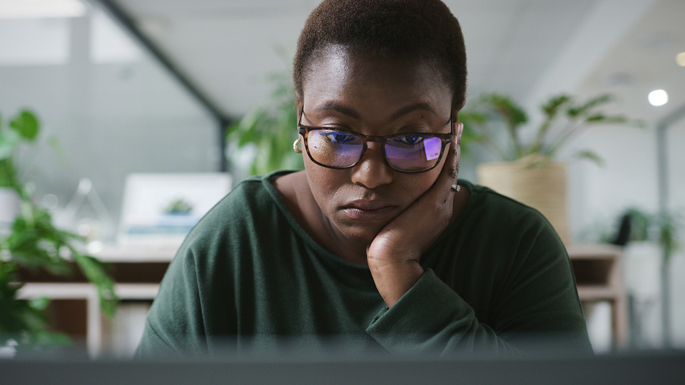 A woman wearing glasses looks at a computer screen