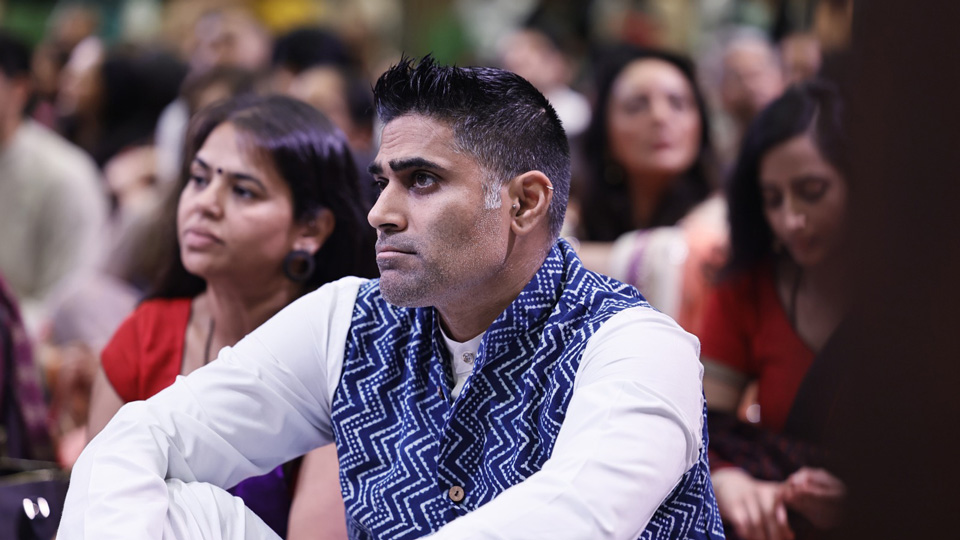 Rajesh Chandegra sits on the floor among a crowd as part of Janmashtami celebrations