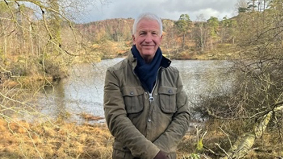 Simon is dressed for the cold and photographed in an autumnal lake landscape