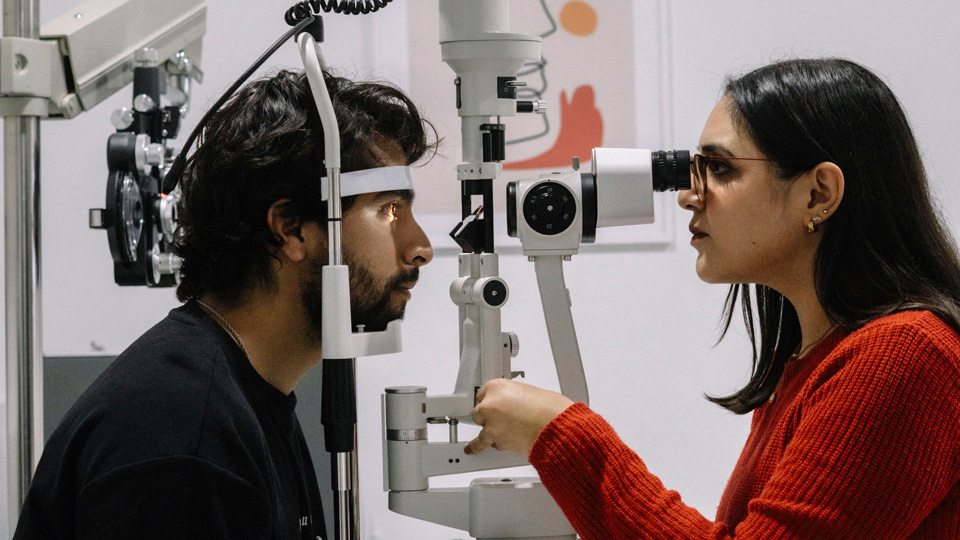 A female optometrist is performing a slit lamp exam for a patient