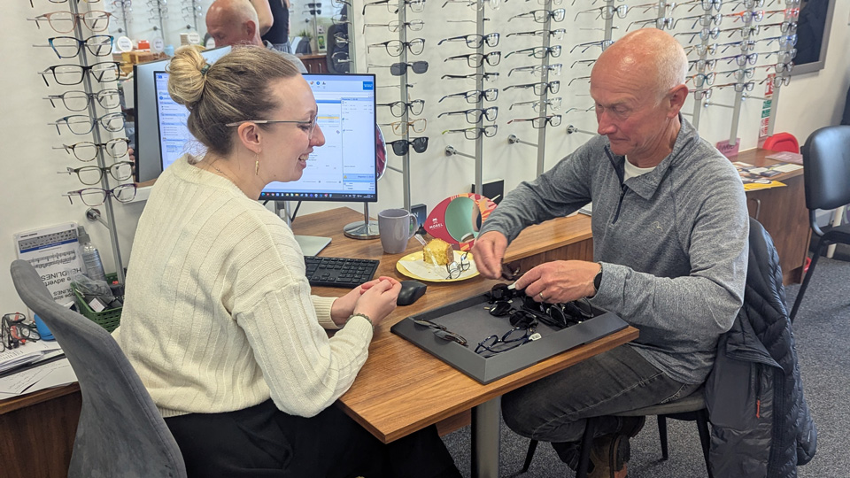 A practitioner sits with a member of the public in an optometry practice, they are chatting and looking at frames