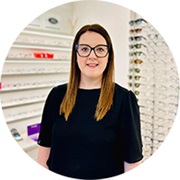 Emma Harris smiles whilst stood inside an optometry practice