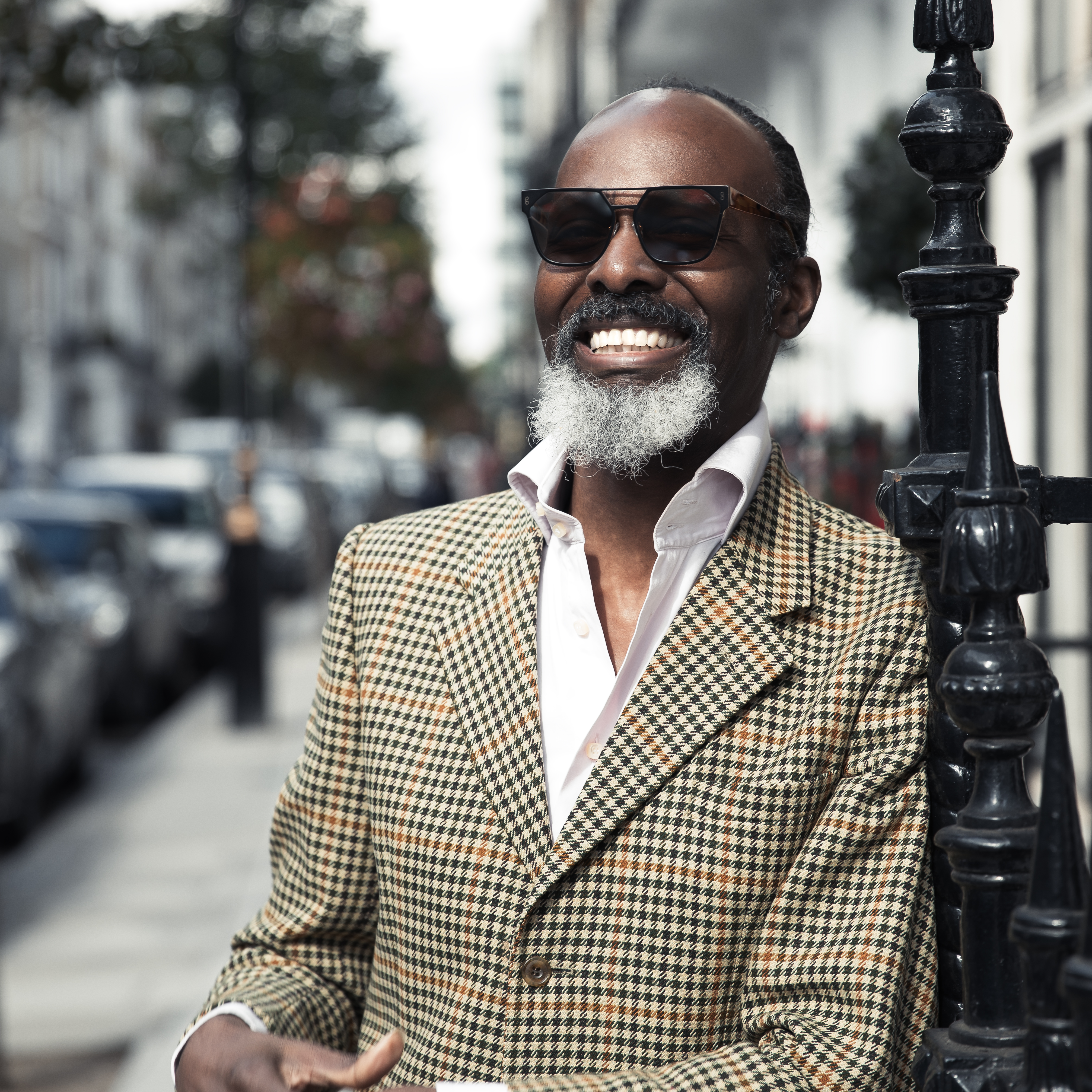 Antony wears a light brown tweed jacket and smiles