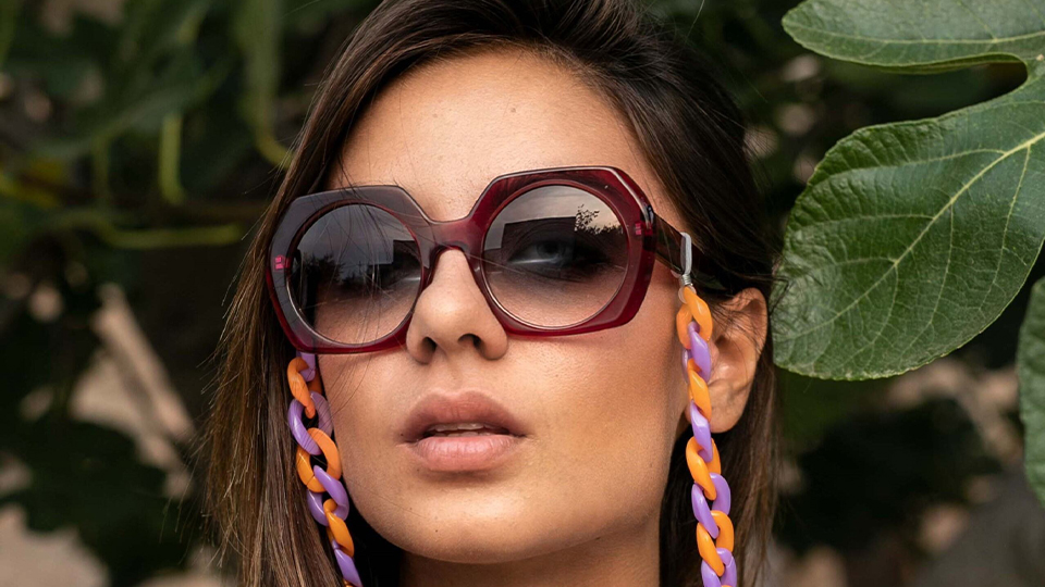 A model poses with a chunky glasses chain of orange and lilac