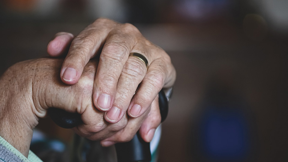 Hands hold the top of a walking cane