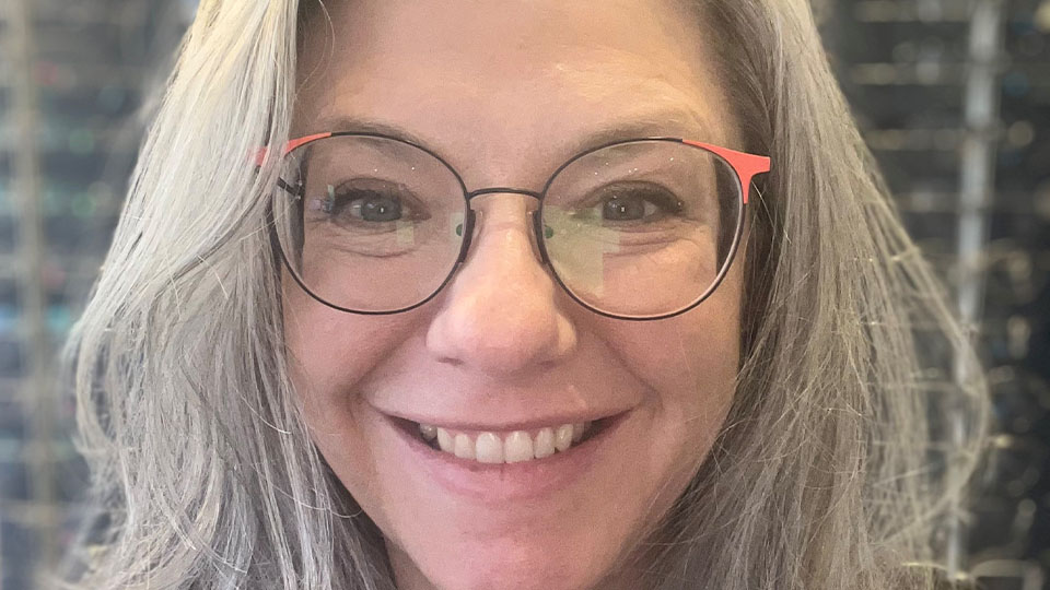 Pam has long grey hair and is smiling directly at the camera  
