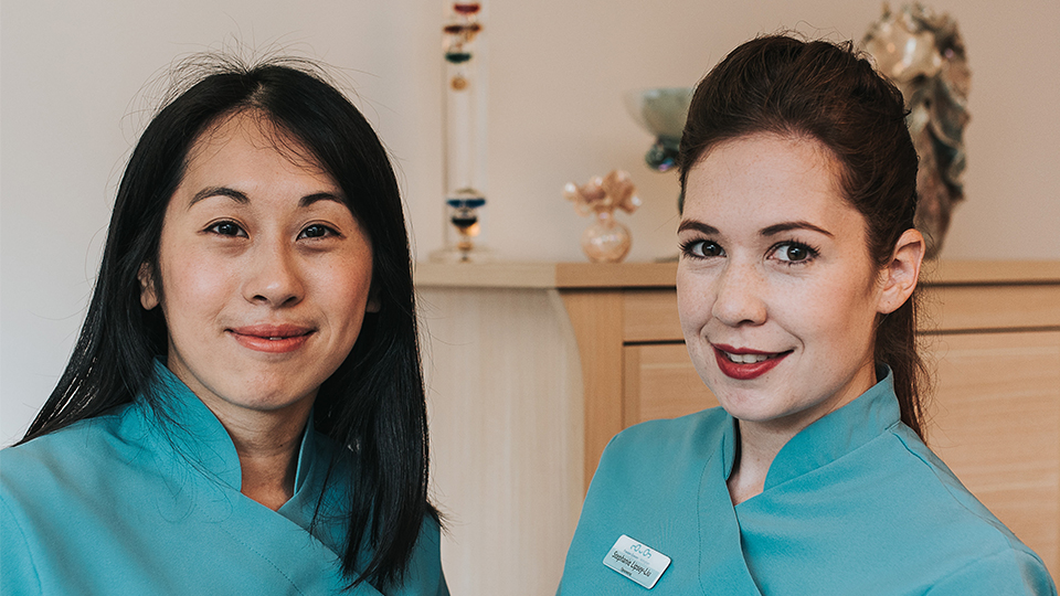 Steph and Ann are stood inside smiling at the camera in their uniforms  