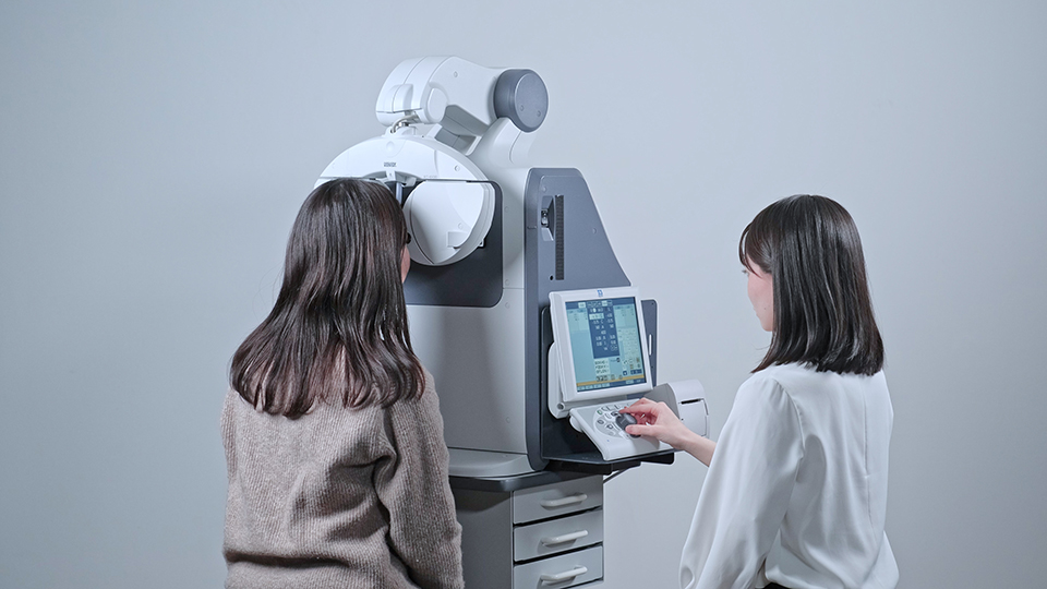 A person is positioned for a measurement from a medical device, another person is operating it