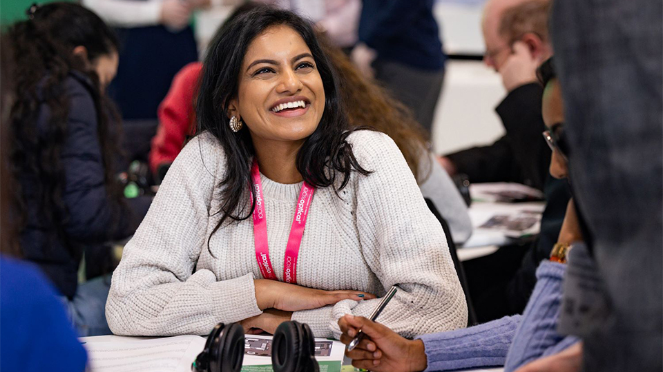 An attendee of a discussion session at 100% Optical laughs with a moderator 