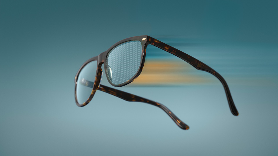 A pair of sunglasses with blue lenses are waved through a sunny, green, space. The movement creates a blur effect. A hexagonal pattern across the lenses, and in the background of the indicate, indicate technology