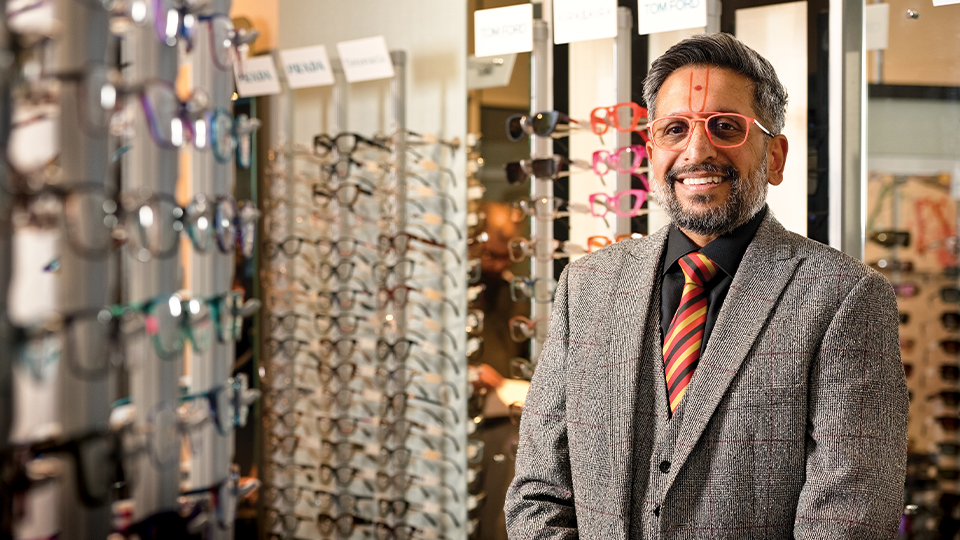 Dr Keyur Patel stands in front of a glasses display in practice