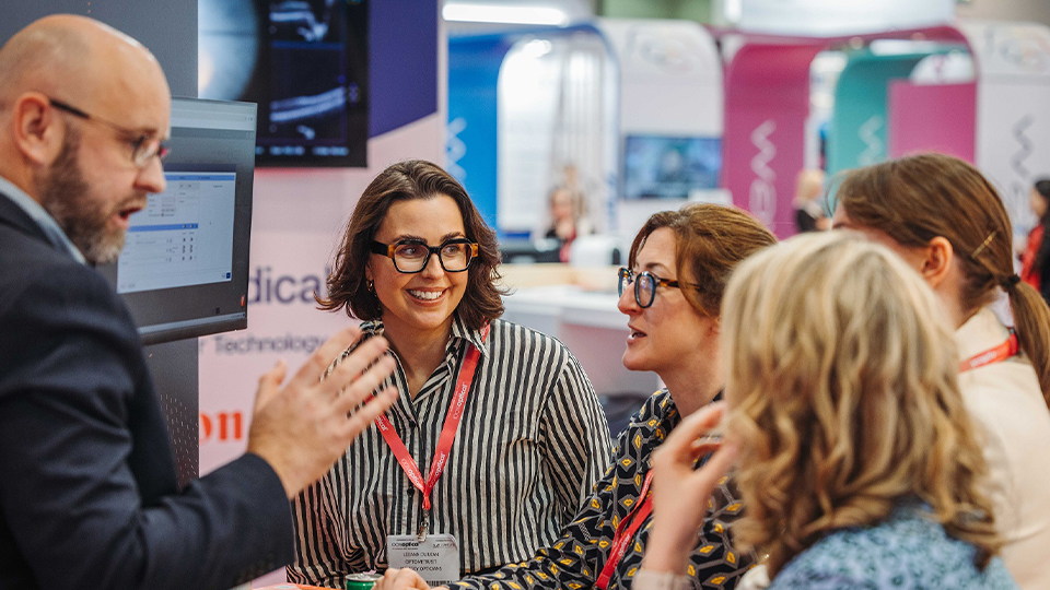A group of delegates speak with an exhibitor at the show