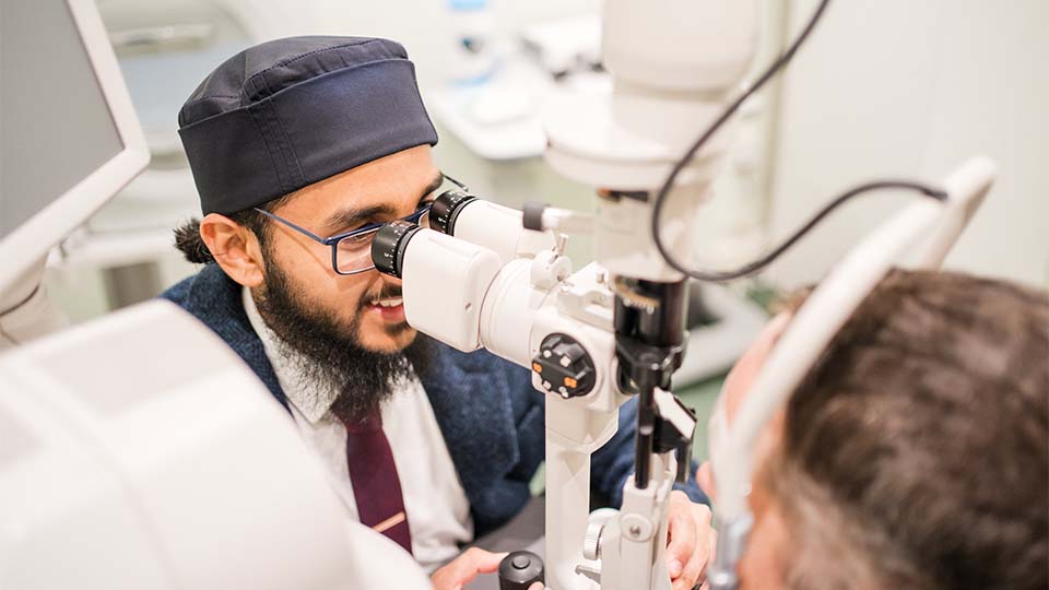 Habeeb is performing an eye test on a patient in a consulting room